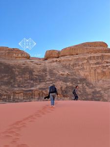 瓦迪拉姆的住宿－aالكـريـم AL KARIM LUXURY CAMP，两个人在沙漠中穿过沙子