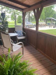una terraza de madera con 2 sillas y una mesa en Disarmingly Cozy 1BR Cabin, en Henderson