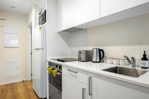クライストチャーチにあるCitypad Studio Apartmentのシンクとコンロのある白いキッチン