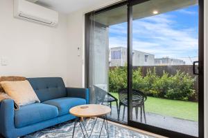 クライストチャーチにあるCitypad Studio Apartmentのリビングルーム(青いソファ、ガラスの引き戸付)