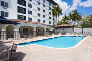 una piscina frente a un hotel con mesas y sillas en Courtyard by Marriott Fort Lauderdale Weston en Weston