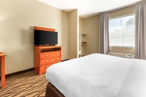 a hotel room with a bed and a flat screen tv at Comfort Inn & Suites Chesapeake - Portsmouth in Chesapeake