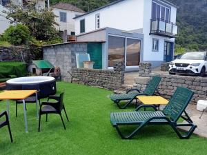 um quintal com cadeiras e mesas e um grelhador em Lombada Villa Comfort em Ponta Delgada