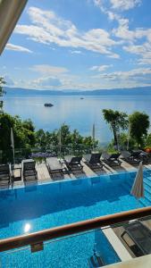 a swimming pool with chairs and a view of the water at Golden Sunset Apartments in Ohrid