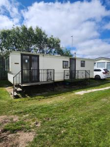 a mobile home with a porch and a car at Fantasy Island Promenade 513 4 Berth in Ingoldmells