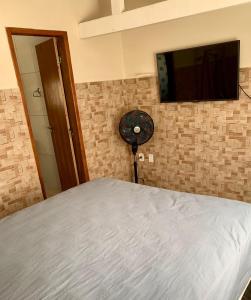 1 dormitorio con 1 cama y TV en la pared en Recanto do Peixe Dourado kitnet en Casimiro de Abreu