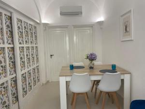 a dining room with a wooden table and white chairs at Casa Amelia in Capri