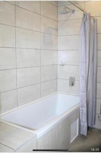 a white bath tub in a white tiled bathroom at Thito Manor Apartment in Maun +12 photos