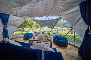 a living room with blue couches and a large window at Glamping Slapy in Slapy