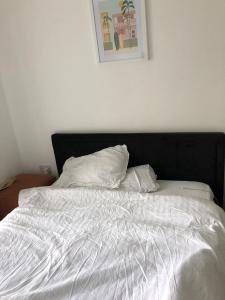 un letto bianco con testiera nera e 2 cuscini di Impeccable 2-Bed Apartment in Orpington a Orpington