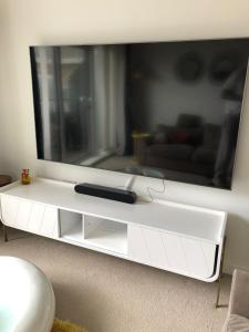 un centro de entretenimiento blanco con una gran televisión en la pared en Impeccable 2-Bed Apartment in Orpington, en Orpington