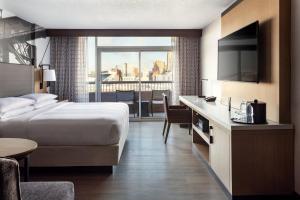 a hotel room with a bed and a desk with a television at Cincinnati Marriott at RiverCenter in Covington