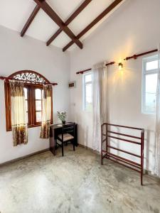 a bedroom with a bed and a desk and windows at Light House View Inn - Galle Fort in Galle