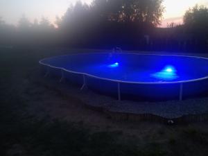 a large blue swimming pool in a field at sunset at zakątek pod świerkami in Gulbiny