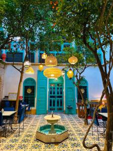 une cour avec une fontaine en face d'un bâtiment bleu dans l'établissement Riad Al Nour, à Marrakech