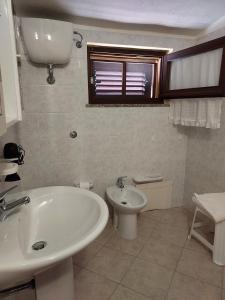 Baño blanco con lavabo y aseo en La Rosa dei Venti B&B en Chia
