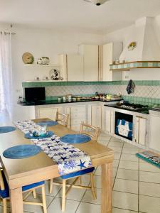 una cocina con mesa de madera con sillas y una cocina con armarios blancos. en Villa Liuba, en Isquia