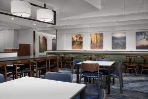 uma sala de jantar com mesas, cadeiras e pinturas em Fairfield Inn & Suites By Marriott Sioux Falls Airport em Sioux Falls