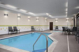 una piscina en una habitación con sillas y mesas en Fairfield Inn & Suites By Marriott Sioux Falls Airport, en Sioux Falls