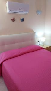 a bedroom with a pink bed with a pink blanket at La Rosa dei Venti B&B in Chia