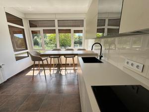 a kitchen with a table and chairs and windows at Chalet Sanxenxo - A Lanzada in Sanxenxo