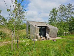 a small shed with two chairs in a field at Tiny House De Skries in Westergeest +12 photos