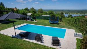 - une piscine avec 2 chaises et un parasol dans l'établissement Family House, à Krčedin