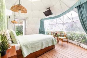 una camera da letto con un letto, un tavolo e una finestra di Ubuntu Glamping a Guanacaste
