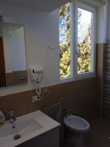 bagno con lavandino, servizi igienici e finestra di Bougainvillea casa vacanza a Castelbuono