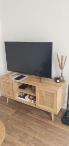 a wooden entertainment center with a flat screen tv on it at Charmant logement neuf in Hourtin