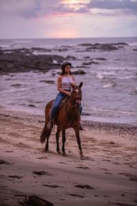 Una mujer montando a caballo en la playa en Luxury Vacation Rentals At Hacienda Pinilla, en Tamarindo
