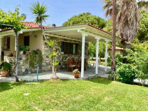 a house with a white pergola in a yard at Apartment Nina Holidays in Paralia Sikias