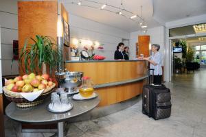 a woman standing at the counter of a hotel with a suitcase at Hotel Unger in Stuttgart
