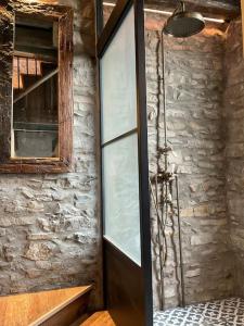 a shower in a room with a stone wall at The Tobacco Loft in Kendal