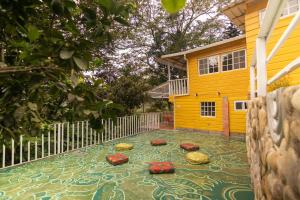 a yard with a yellow house with a mosaic floor at Nan La Tigra in El Rosario