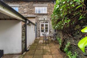 a patio with a table and chairs in front of a building at Roseberry Cottage in Ambleside