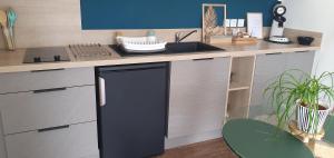a kitchen with a sink and a black dishwasher at Charmant logement neuf in Hourtin