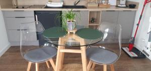 a glass table with two chairs and a plant on it at Charmant logement neuf in Hourtin