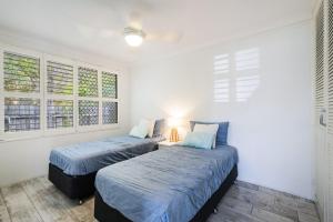Duas camas num quarto com paredes brancas e janelas em Iluka Villa 9 em Iluka