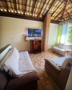 a living room with a couch and a bed and a television at SITIO AMANHECER VERDE in Contagem