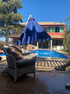 um guarda-chuva azul sentado numa cadeira ao lado de uma piscina em SITIO AMANHECER VERDE em Contagem