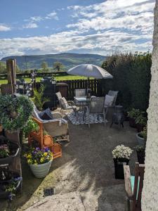- une terrasse avec des chaises, un parasol et des fleurs dans l'établissement Cosy cottage Atlantic way, à Carnlough