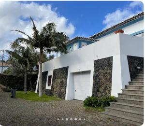 una casa bianca con un garage e una palma di Quinta de Santo António a Fonte do Bustardo