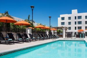 a pool with chairs and umbrellas next to a building at Residence Inn by Marriott Los Angeles Pasadena/Old Town in Pasadena
