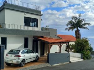 Biały dom z samochodem zaparkowanym przed budynkiem w obiekcie Vаrаndаs dо Sоl-Vista relaxante entre mar e montanha w mieście Ponta do Sol