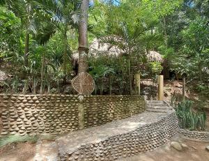 a stone wall with a sign in front of trees at Magdalena Beach House in Los Naranjos