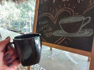 a person holding a coffee cup next to a chalkboard at Magdalena Beach House in Los Naranjos