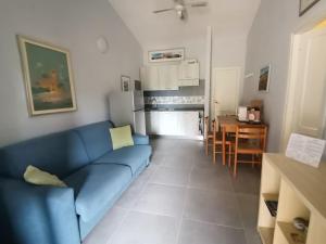 sala de estar con sofá azul y cocina en Casa di Giò - Bilocale con giardino, en Porto Pollo