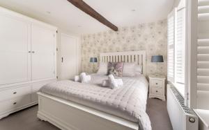 a white bedroom with a large white bed with pillows at Ross Cottage in Hawkshead