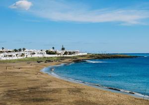 a beach with people in the water and buildings at Garden House, Playa Honda in Arrecife